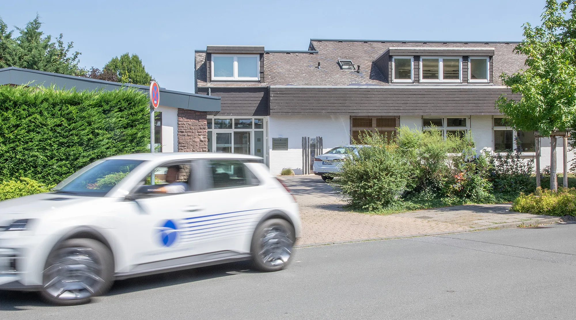 Das Kanzleigebäude der Scheurer-Gruppe in Lippstadt mit vorbeifahrendem Firmenwagen